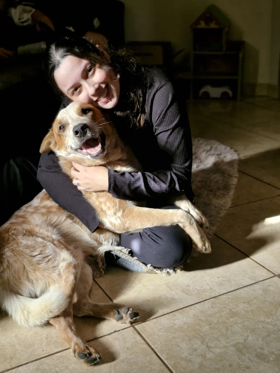 Cachorro sorridente abraçado pela Dra. Vanessa